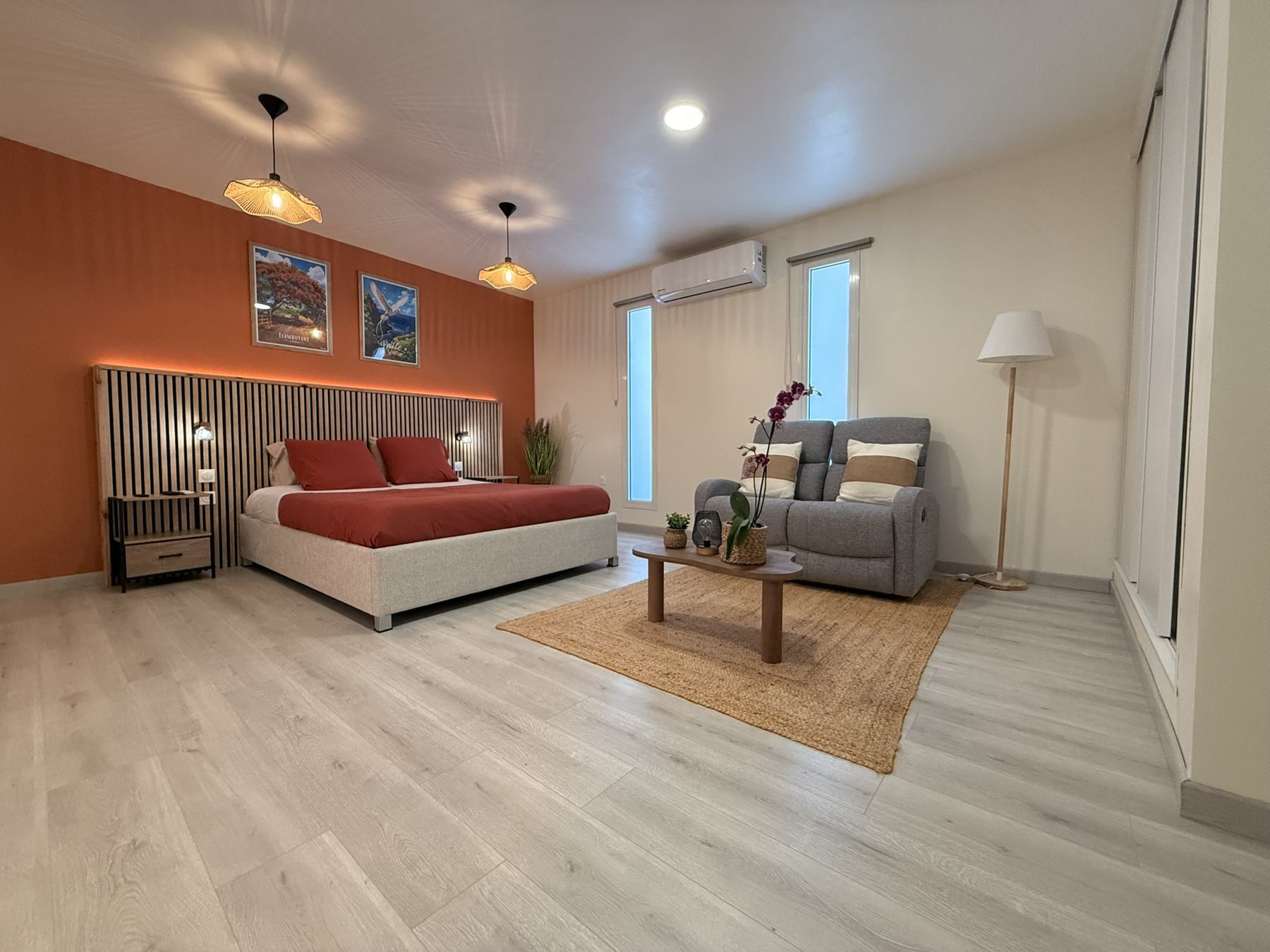 Lit double avec mur terracotta et tête de lit en tasseaux de bois