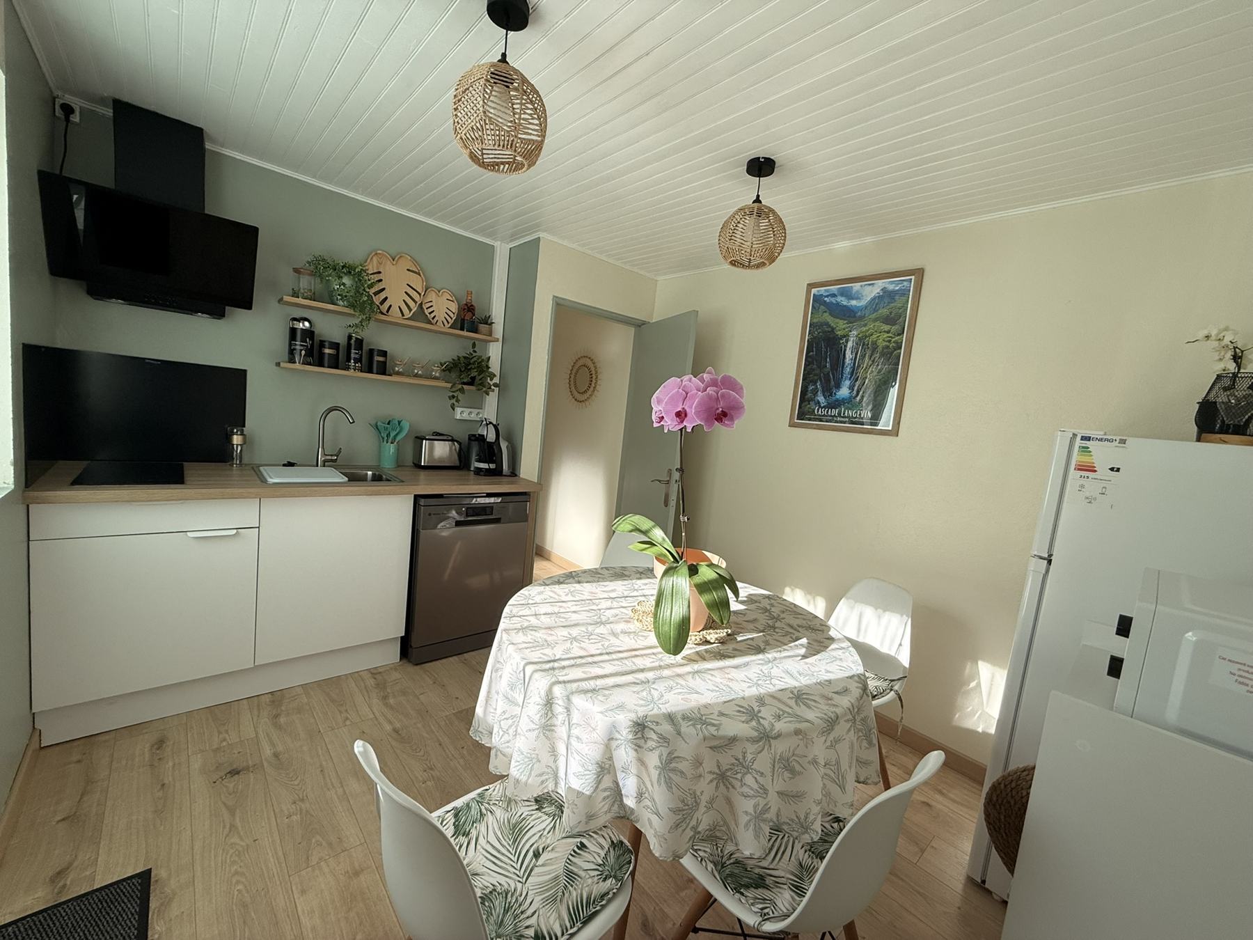 Cuisine ouverte sur coin repas avec table ronde et nappe tropicale